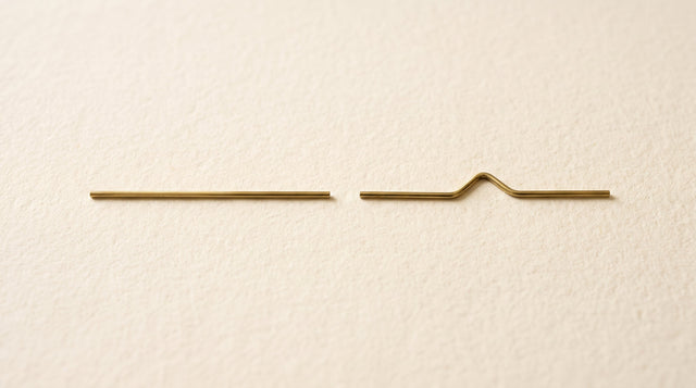 Zwei dünne goldene Drahtstücke im Vergleich: eine gerade Linie und eine geknickte Form symbolisieren die all-trans- und cis-Struktur von Vitamin K2 MK-7